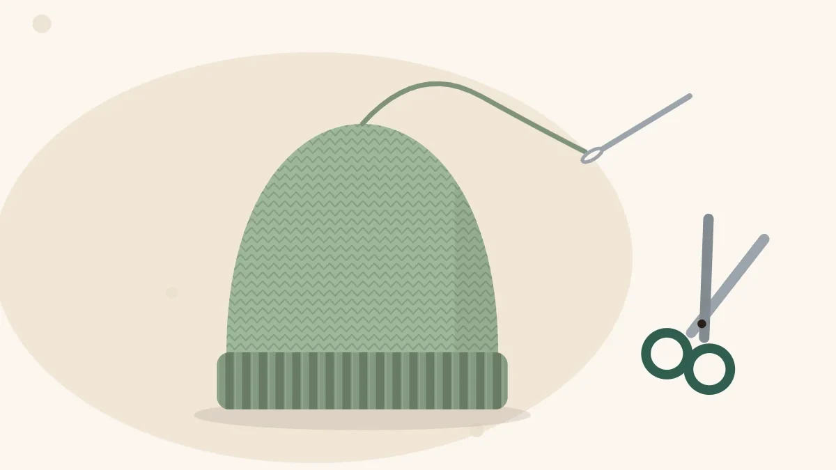 Illustration of a finished knitted hat with a tapestry needle, a loose yarn tail and a pair of scissors beside it
